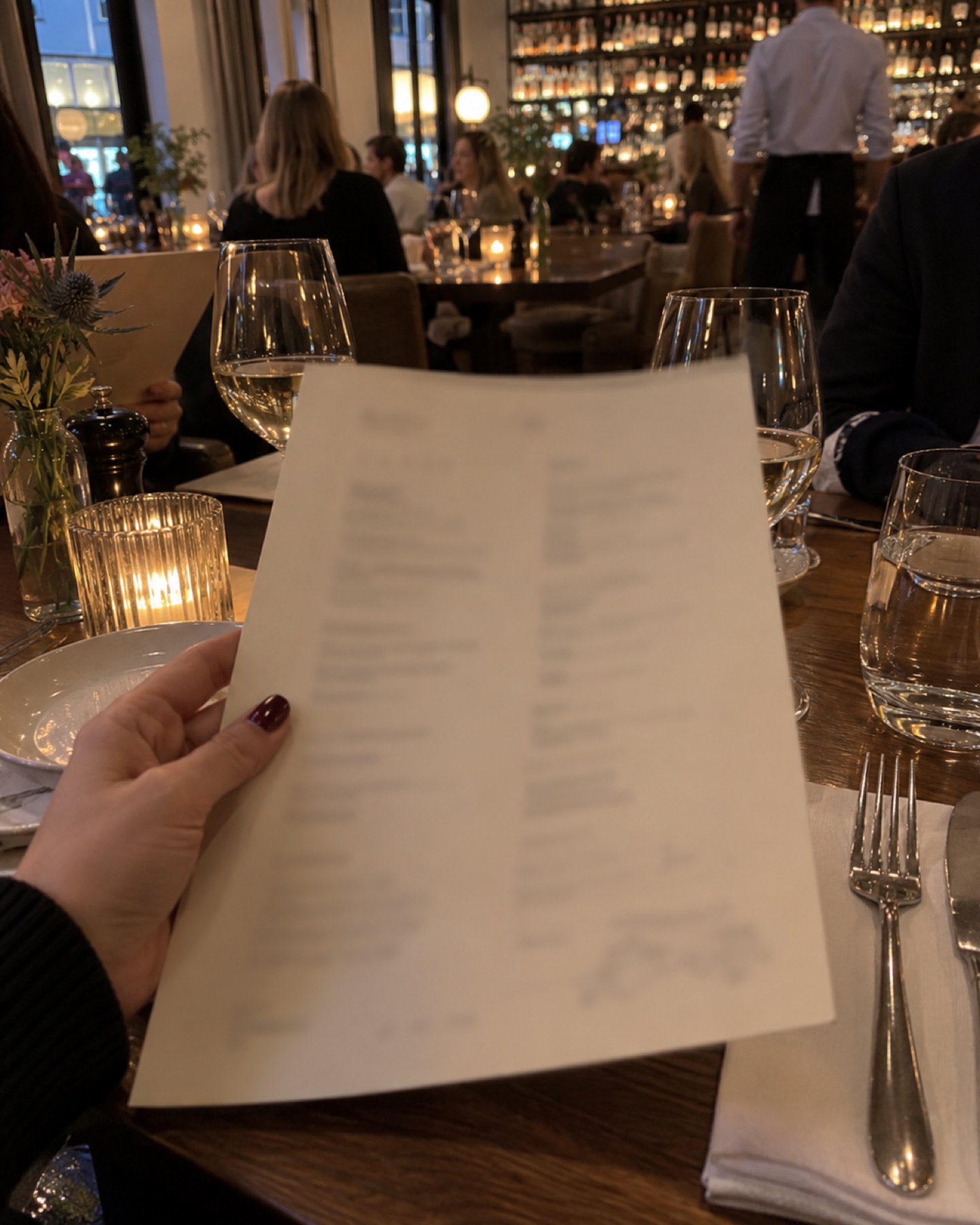 Dłoń trzyma kartę menu nad stolikiem w restauracji, chwila przed zamówieniem.